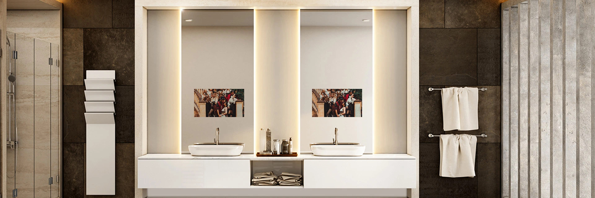 Two white towels on the side of the mirror TV set into a wall of a restroom with double basins.