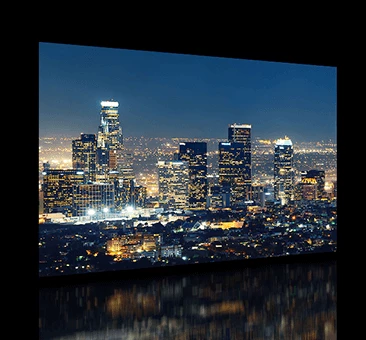 Tall buildings at night in the city are displayed on the TV screen.